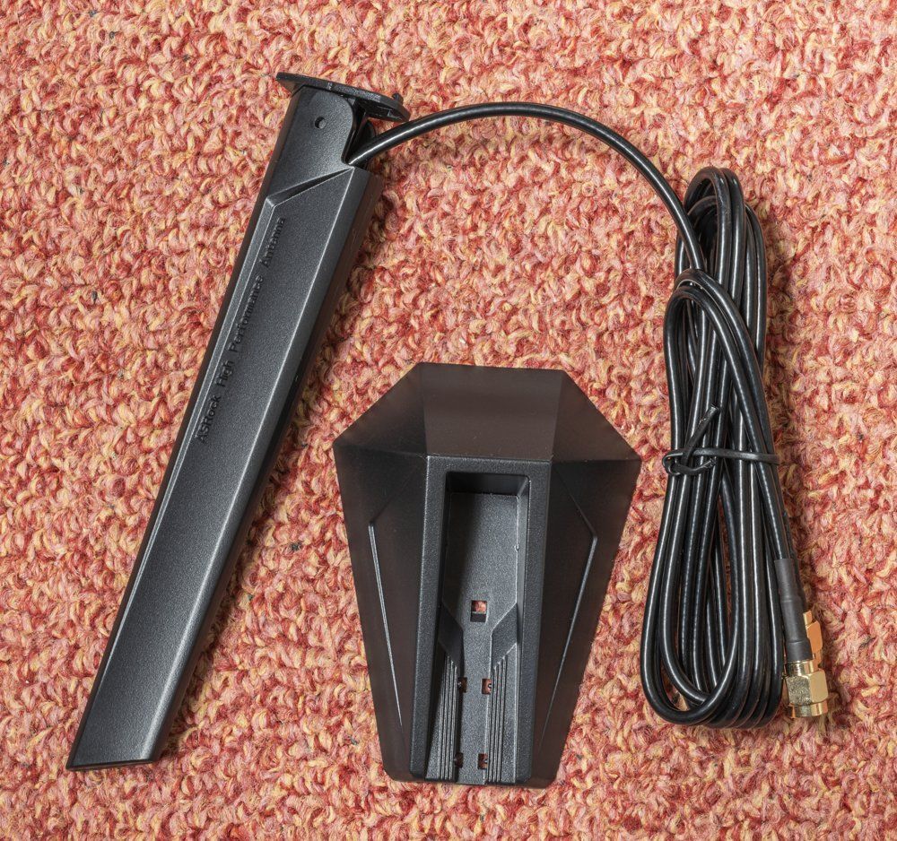 Antenne WiFi magnétique externe livrée avec une carte mère, posée à côté de son socle