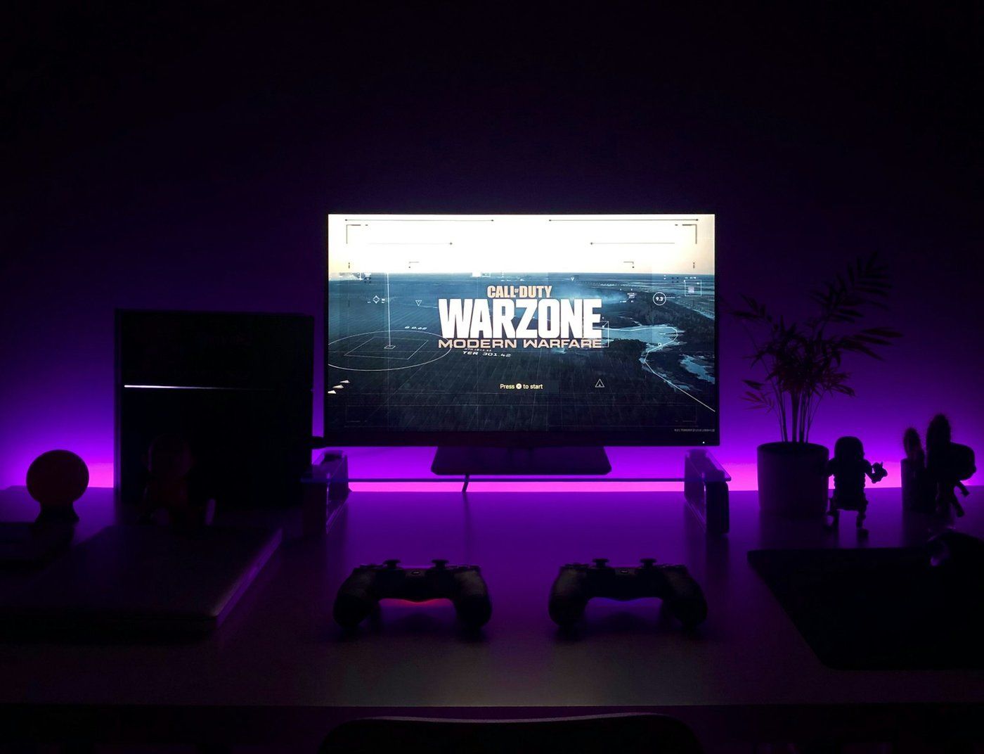 Bureau sombre avec écran gaming allumé et rétroéclairage violet
