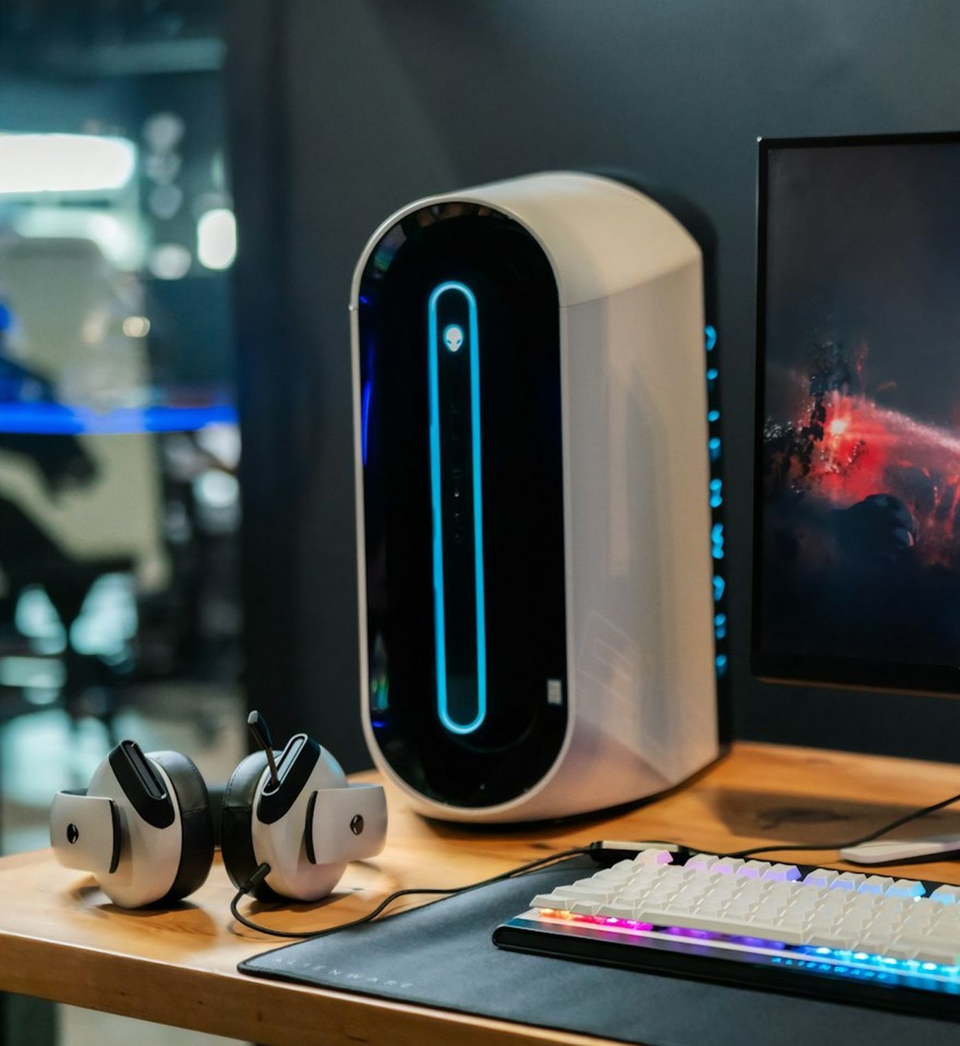 Boîtier compact blanc posé sur un bureau en bois, à côté d’un écran
